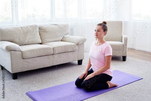 Girl sitting in virasana position and meditating at home interior, copy space. Woman practicing home yoga. Fitness, sport and healthy lifestyle concept