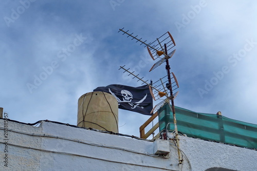 Drapeau pirate et antenne télé sur un toit.