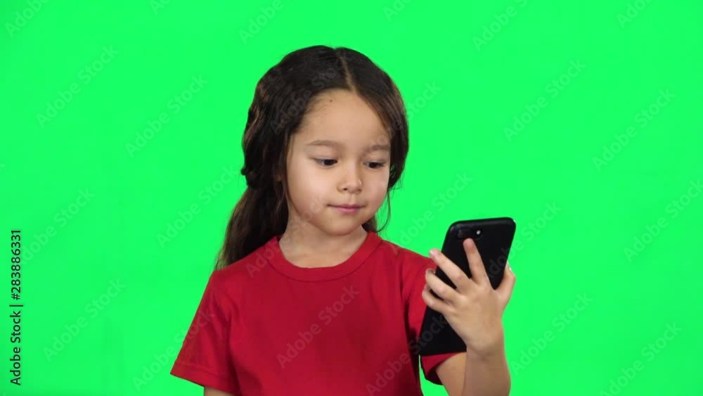 Little dark-haired girl with phone using Video Calling. Slow motion Little dark-haired girl with phone using Video Calling. Slow motion