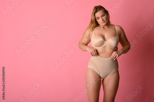 attractive chubby girl in underwear on pink background