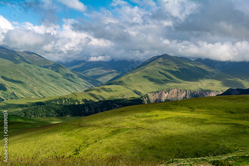 Beautiful view of idyllic alpine mountain scenery with blooming meadows and mountains on a beautiful sunny day with blue sky and clouds in summer.