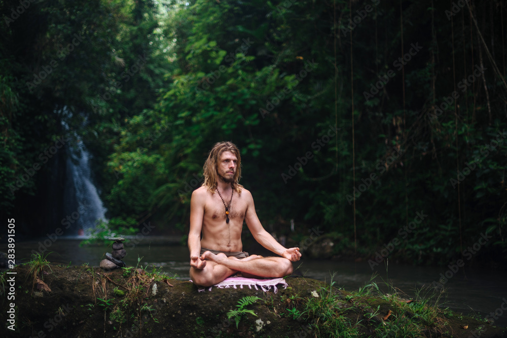 Yoga practice and meditation in nature. Man practicing near river Yoga practice and meditation in nature. Man practicing near river