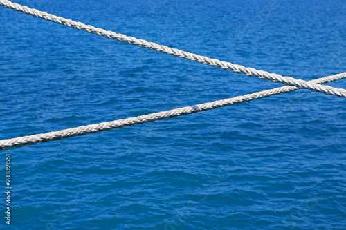 Ship rope against blue water sea texture background. © zilvergolf