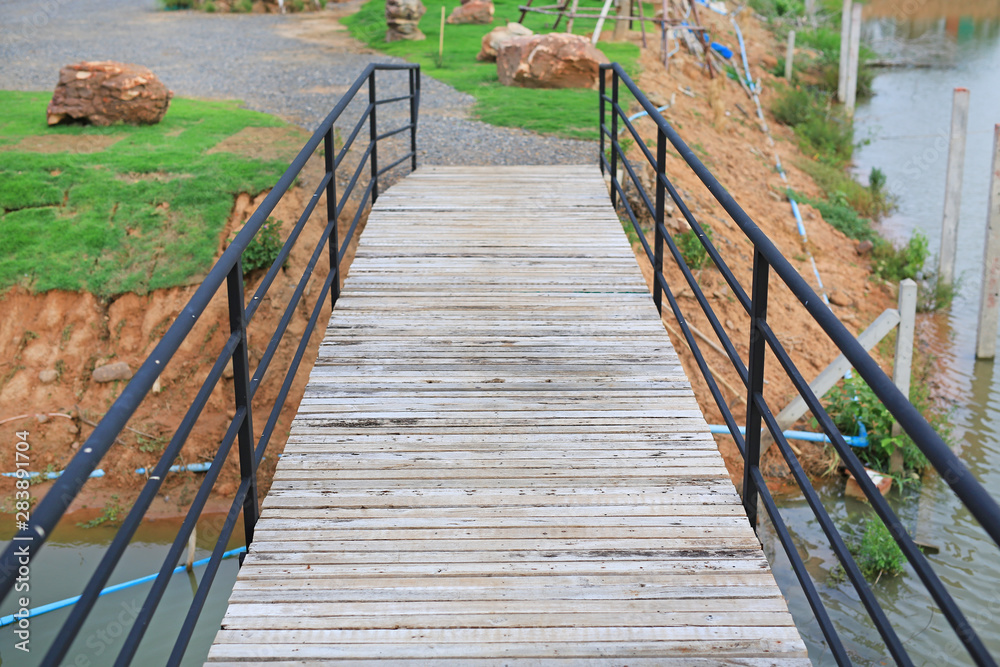 Wooden bridge crossing river to countryside pavilion in Thailand.