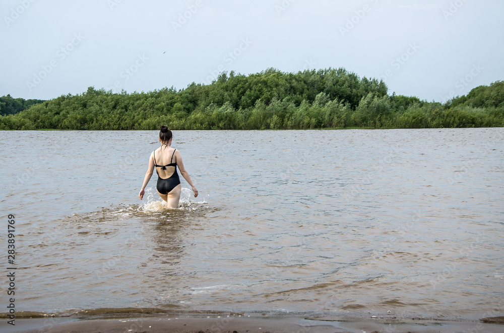 On a warm summer day, the girl goes into the river to swim, copy space. On a warm summer day, the girl goes into the river to swim, copy space.