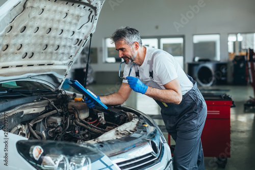 mechanic looking at parts brochure in car service