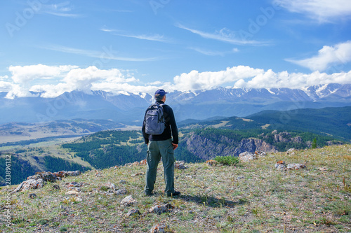 Man hiking in mountains. Man standing on top of cliff in summer mountains and enjoying view of nature.