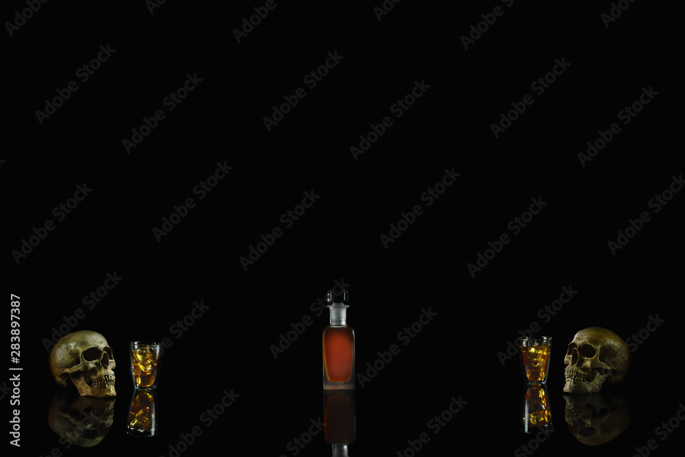 a glass of whisky on the rock with a bottle of whisky and humen skull in concept of stop drinking algolhol drink on dark background a glass of whisky on the rock with a bottle of whisky and humen skull in concept of stop drinking algolhol drink on dark background
