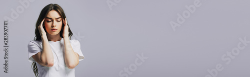 beautiful girl in white t-shirt suffering from headache isolated on grey, panoramic shot photo