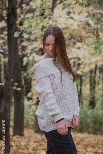 Portrait of a beautiful, dreamy and happy girl with long wavy hair in knit sweater autumn. Nice weather