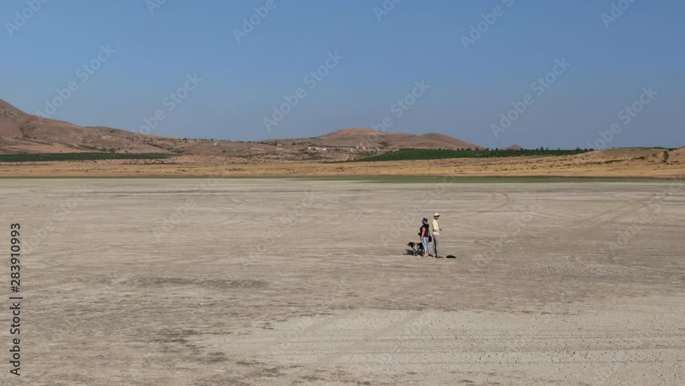Two researchers, a man and a woman, stand in the middle of the desert where there once was a lake. CRIMEA 2019 Two researchers, a man and a woman, stand in the middle of the desert where there once was a lake. CRIMEA 2019
