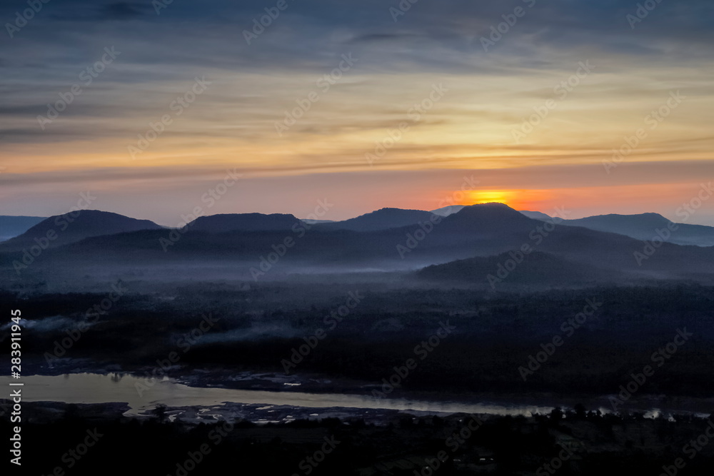 Top view panorama of Mekong river around with soft mist, forest, mountains with cloudy and yellow sun light in the sky background, sunrise at Cha Na Dai Cliff, Ubon Ratchathani, Thailand.