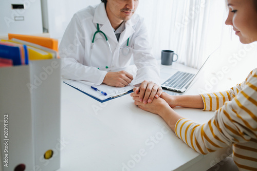 Male doctor cheering up his female patient, holding her hand photo