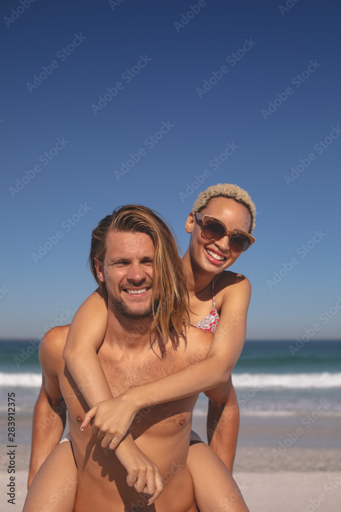 Man giving piggyback ride to woman on the beach