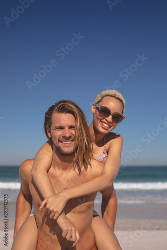 Man giving piggyback ride to woman on the beach