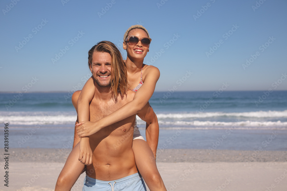 Man giving piggyback ride to woman on the beach Man giving piggyback ride to woman on the beach