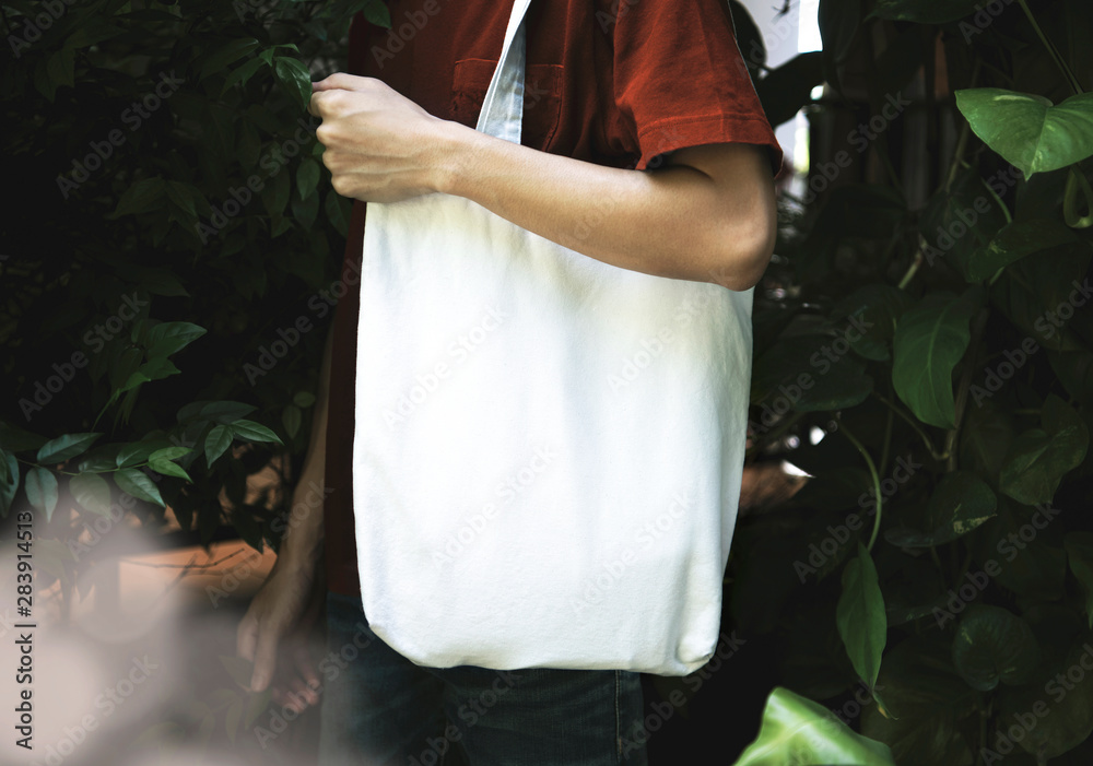Man is holding bag canvas fabric for mockup blank template on nature background.  global warming concept.