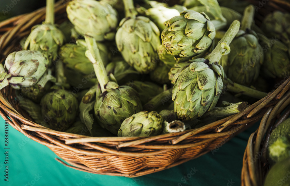 Fototapeta premium Fresh artichokes in wicker at farmers market
