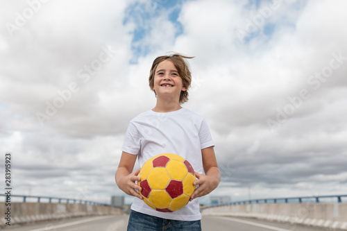 cheerful and smiling boy in white T-shirt and ball