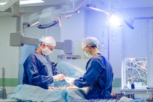 Group of surgeons in operating room with surgery equipment. Modern medical background. In surgery.