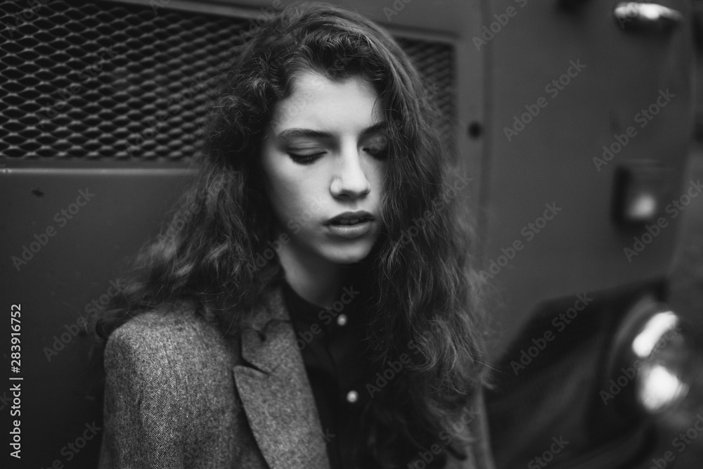 Young beautiful caucasian woman walking in old town. Black and white female art portrait. Stylish girl with long curly hair. Young beautiful caucasian woman walking in old town. Black and white female art portrait. Stylish girl with long curly hair.