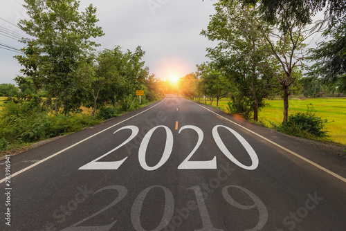 Highway concept for business planning,The word 2020 written on highway road in the middle of empty asphalt road at golden sunset and beautiful blue sky.