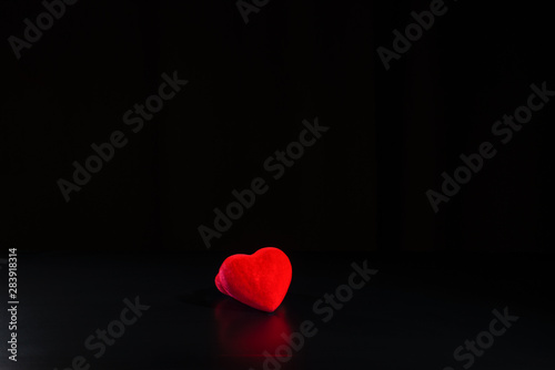Red bright heart is on the black table/background. There is reflection too. International Human Solidarity Day