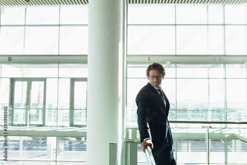 Businessman leaning on railing and looking away in a modern office building Businessman leaning on railing and looking away in a modern office building