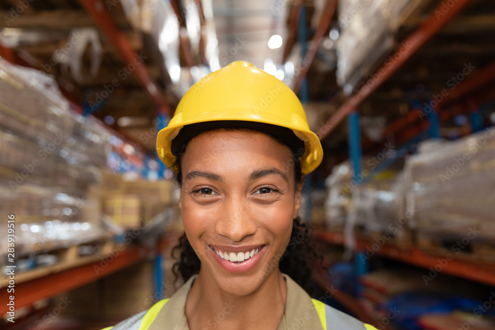 Happy female worker looking at camera in warehouse Happy female worker looking at camera in warehouse