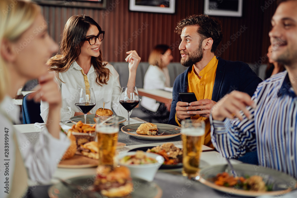 Multiethnic friends sitting at restaurant, drinking alcohol, chatting and having burgers for dinner. Multiethnic friends sitting at restaurant, drinking alcohol, chatting and having burgers for dinner.