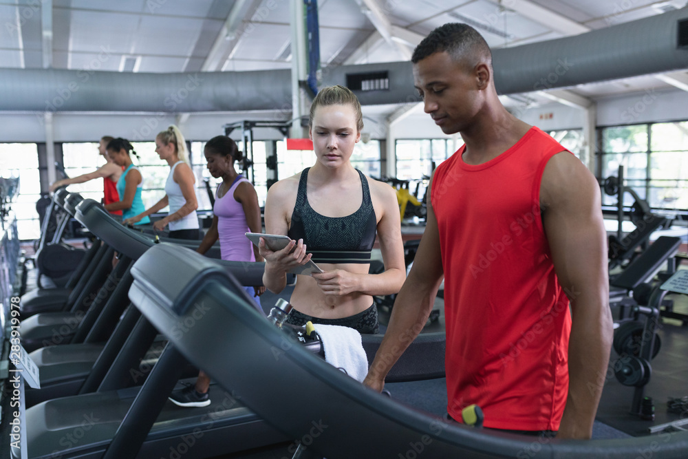 Female trainer assisting man to work out on treadmill Female trainer assisting man to work out on treadmill