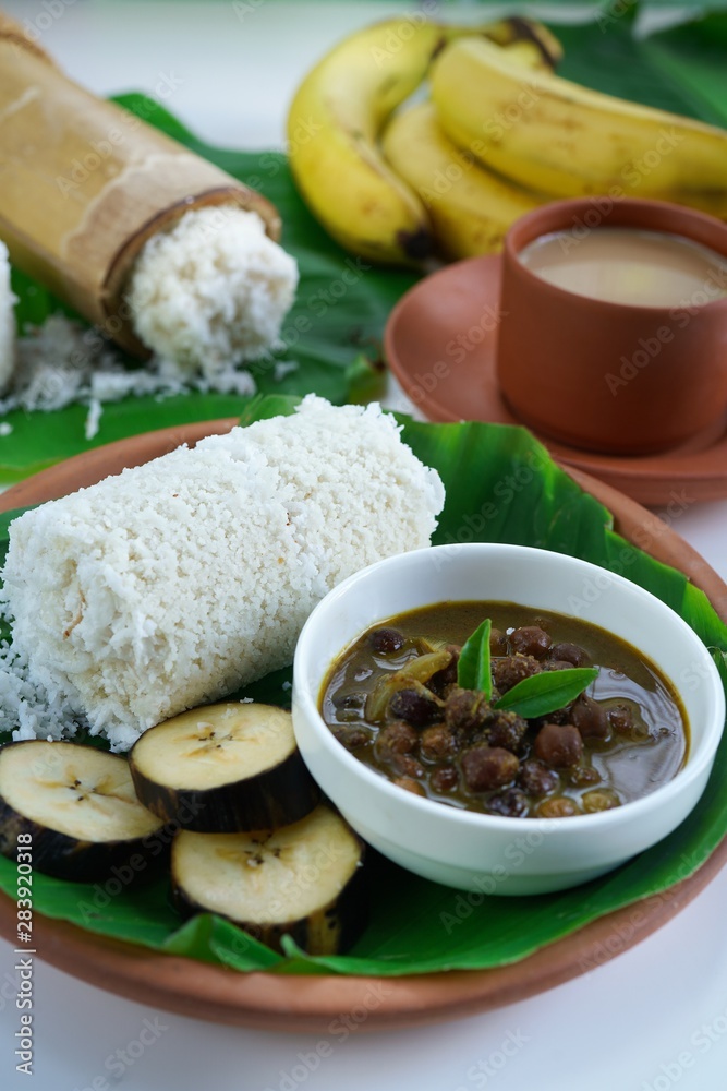 Kerala breakfast rice Puttu /Pittu made in bamboo mould served with Kadala curry banana papad and tea on banana leaf
