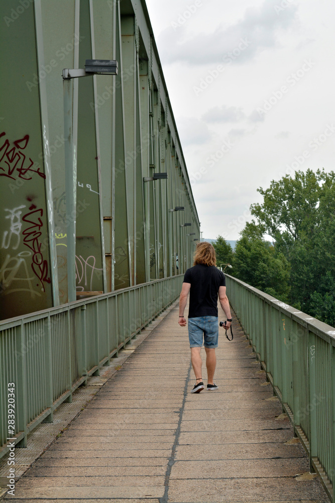 ein mann geht auf der mainzer kaiserbrücke