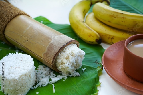 Kerala breakfast rice Puttu /Pittu made in bamboo mould served with Kadala curry banana papad and tea on banana leaf photo