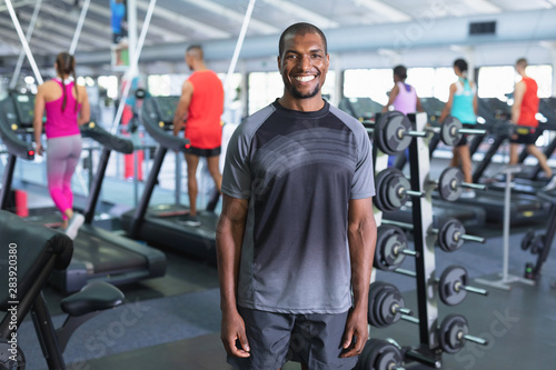 Happy man looking at camera while standing in fitness center