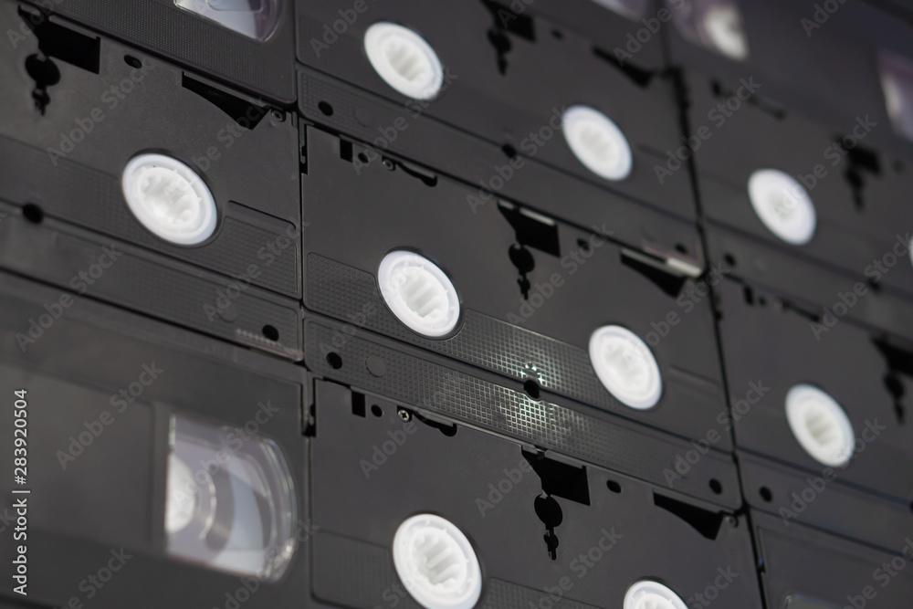 Set of old audio VHS tape on the wall background, large collection of analog black magnetic record technology Set of old audio VHS tape on the wall background, large collection of analog black magnetic record technology