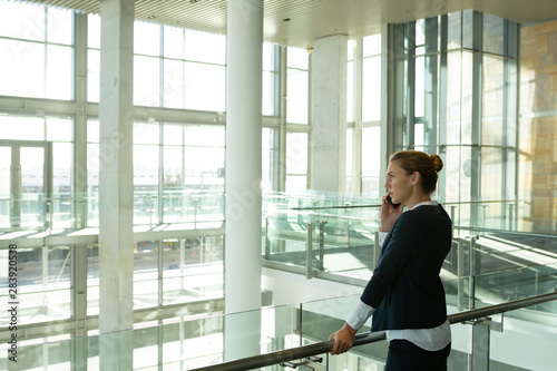 Businesswoman talking on mobile phone near railing in a modern office building