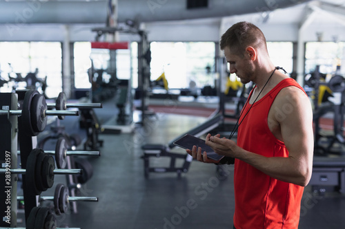 Male trainer using digital tablet in fitness center