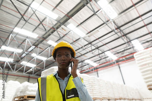 Female worker talking on mobile phone in warehouse