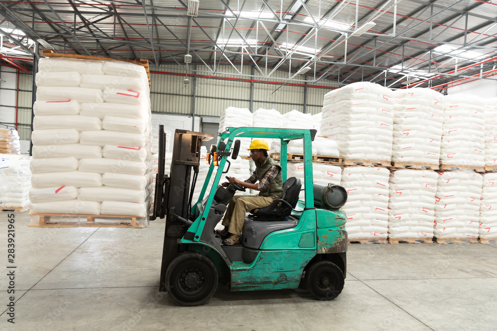 Female worker driving forklift in warehouse