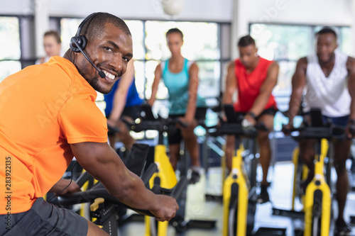 Male trainer training people to work out on exercise bike