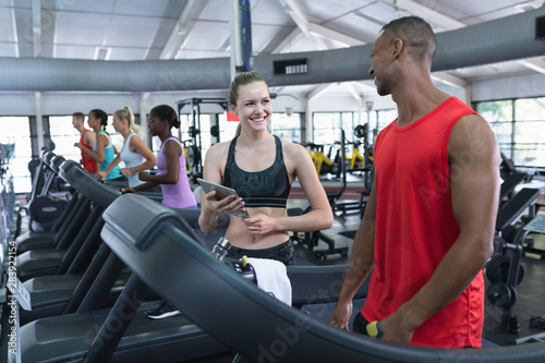 Female trainer assisting man to work out on treadmill
