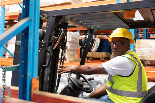 Male staff driving forklift in warehouse