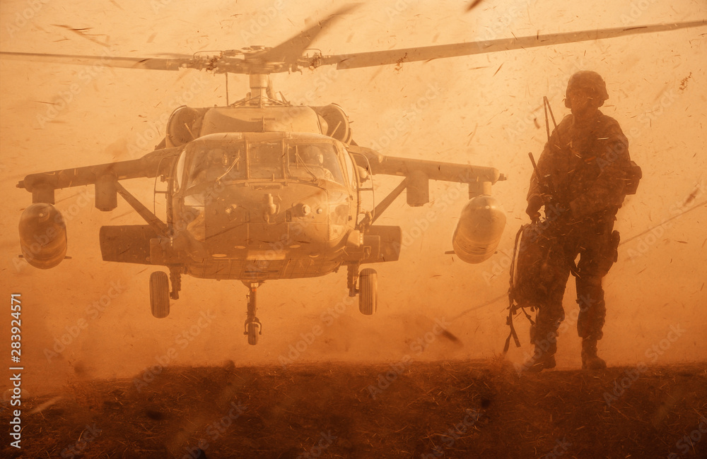 Military soldier walking at desert in front of helicopter in sand storm ...