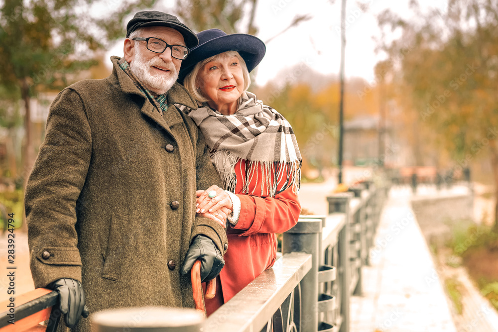 Senior couple posing on a bridge in autumn