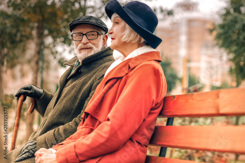 Senior man looking lovingly at his wife sitting on bench in park