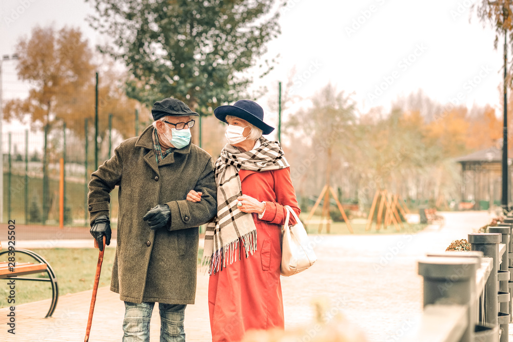 Elderly couple wearing face masks walking in park