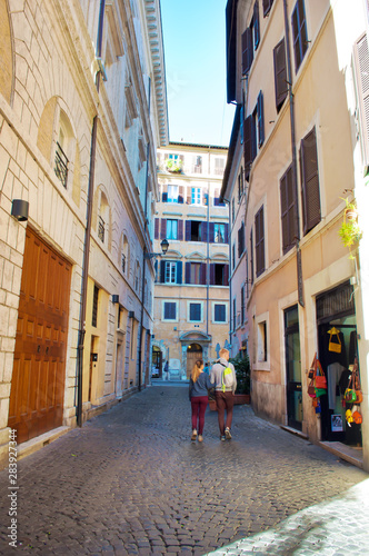 Young man and woman walking down a narrow solitary street in the city center of Rome