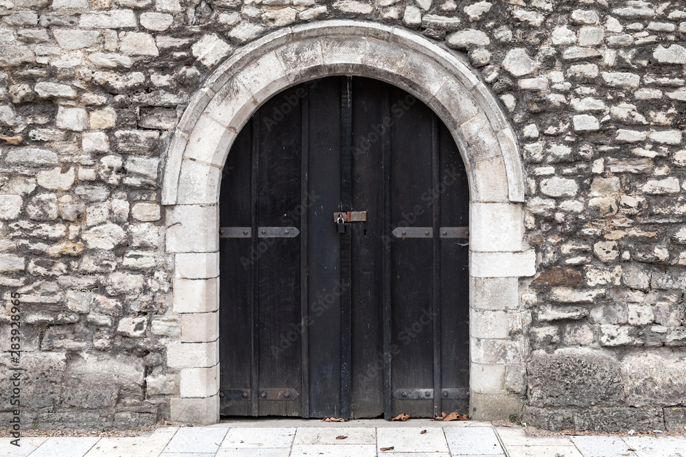 Closed black wooden door in stone wall