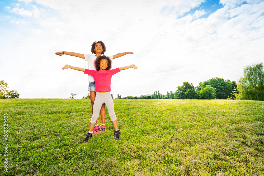 Happy two little girls sisters wave hands at park Happy two little girls sisters wave hands at park